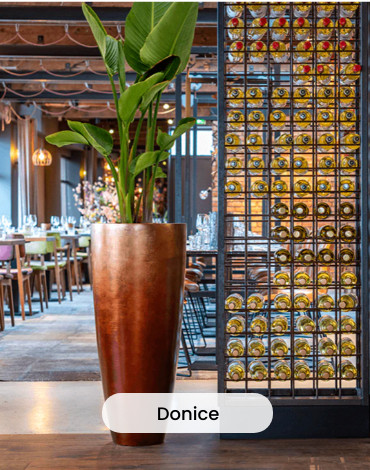 Wysoka donica ze sztuczną rośliną stojąca w restauracji